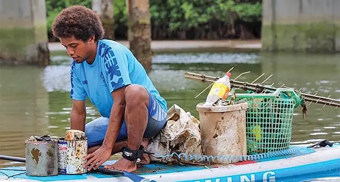 Epeli Lalagavesi colleting rubbish on his Stand-up paddle board.  