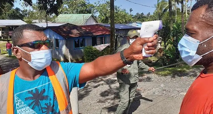 Wainadoi villager Sowani Asaeli (left), uses a thermal gun to take the body temperature of Qorio Davetavalu before allowing him into the village on July 25, 2021. Photo: Ronald Kumar
