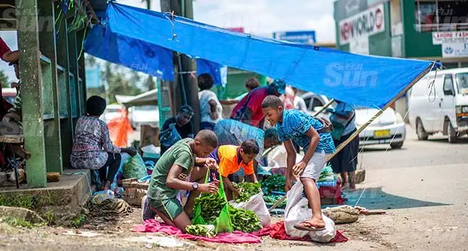Children of market vendors in Nakasi, Isikeli Kuruilaselevu 14, Etuare Nagia 7, and Yabaki Soqila 14, packing up whatever their leftover produce to sell elsewhere after they were told to pack up and demolish their makeshift roadside market on January 12, 2021. Photo: Leon Lord