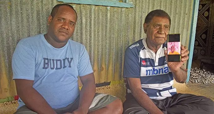 Jeremaia Nakoula (right) holding a photo of his late son, Eparama Naivolasiga, alongside his cousin, Navitalai Bakewa at their home at Tau Village in Nadroga on May 23, 2022. Photo: Nicolette Chambers