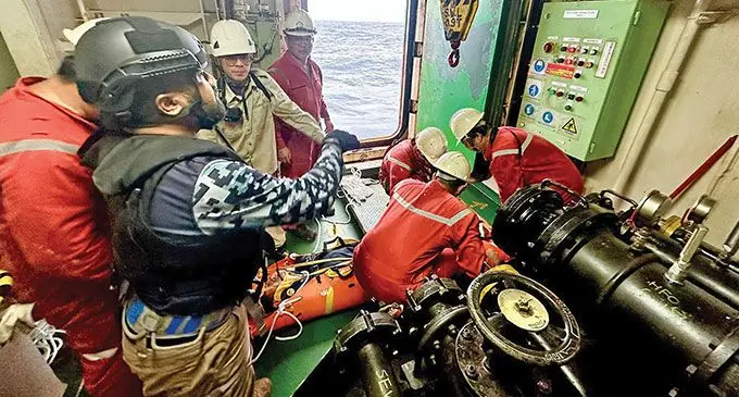 A Fiji Naval personnel and the crew of the cargo ship MV Ever Lunar secure the patient to have him ready to be evacuated.