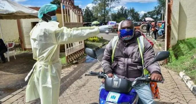 A healthcare worker checks the body temperature of a motorcycle rider visiting the Nakuru County Level 5 Hospital in Nakuru, Kenya, May 7, 2020. (Xinhua/Sheikh Maina)