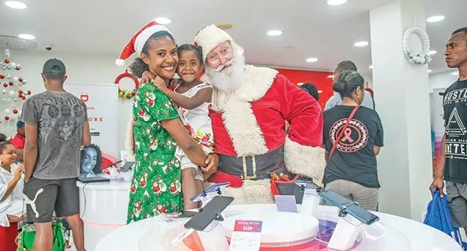 From left: Digicel staff member Varisila Senigasau poses for a photo with Siteri Cakau and in-store Santa Clause during the opening of the Digicel Cumming Street shop on December 4, 2020.  Photo: Leon Lord