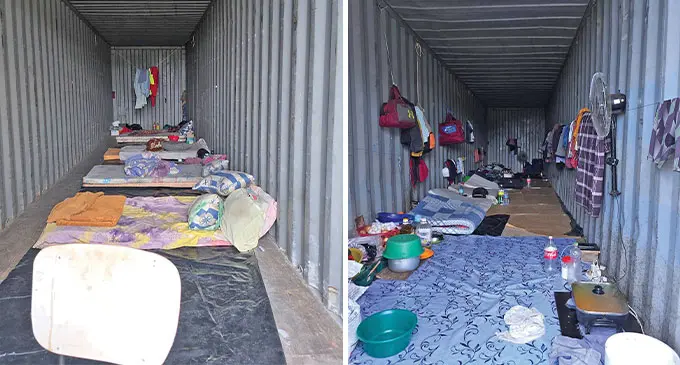 A photograph of two shipping containers with makeshift sleeping and living arrangements depicted. 