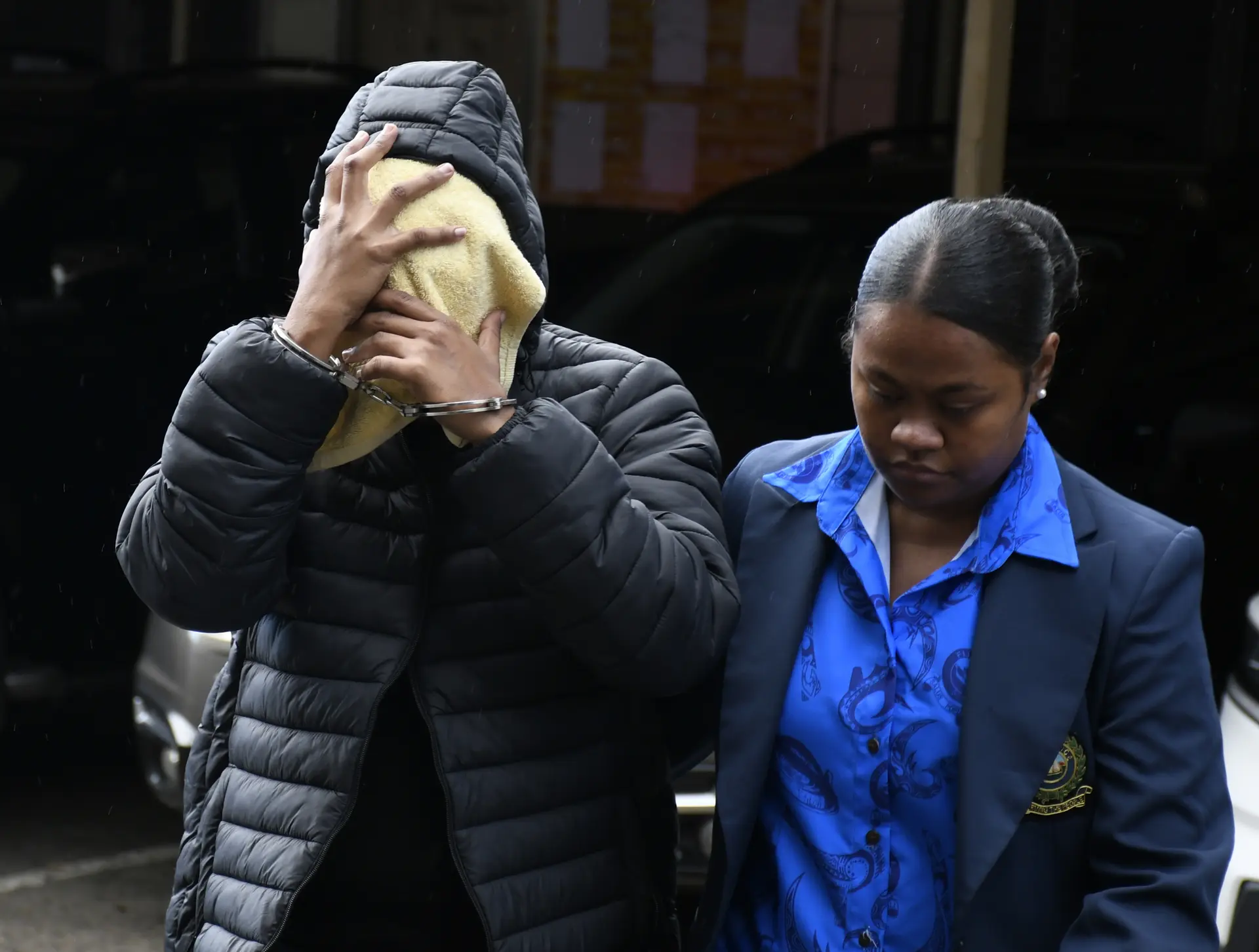 Nilanti Narishna Chand, face covered, escorted by an officer to the Suva Magistrate Court on July 10, 2026.