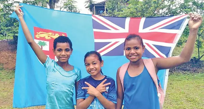 Vinaisi Vuira’s cousins holding Fiji Flag at their home in Nausori.