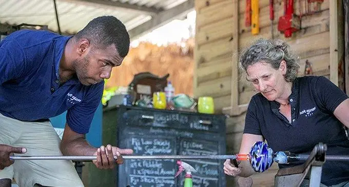 Alice Hill with glass blower and production manager Peter Vibose making a glass piece. 