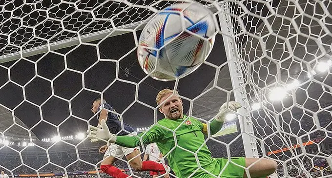 Kylian Mbappe slots the ball past Denmark goalkeeper Kasper Schmeichel at the 974 Stadium in Ras Abu Aboud, Qatar, on November 27, 2022. Mbappe scored twice in France 2-1 win as they became the first team to qualify for the last-16 of the FIFA World Cup 2022. Photo: London Evening Standard.