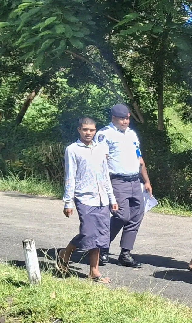 Accused James Robert Moore escorted by a police officer to the High Court in Lautoka. 