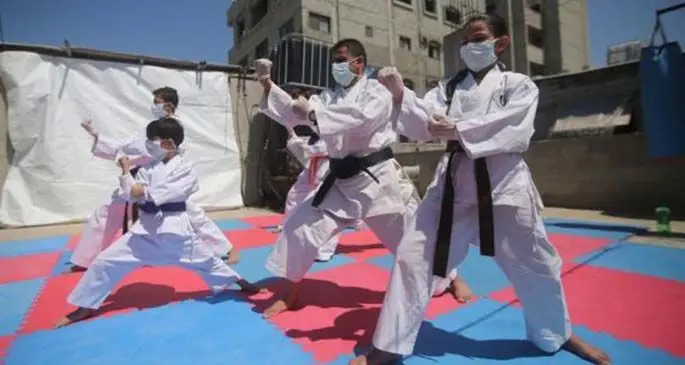 Palestinian Karate instructor Khaled Sheikh Al-Eid (C), trains with his children all wearing face masks due to the COVID-19, on their house roof, in the southern Gaza Strip city of Rafah, on April 12, 2020. (Photo by Khaled Omar/Xinhua)