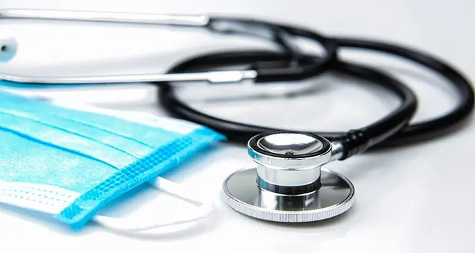 Closed up Stethoscope and Blue Surgical Mask on White Background