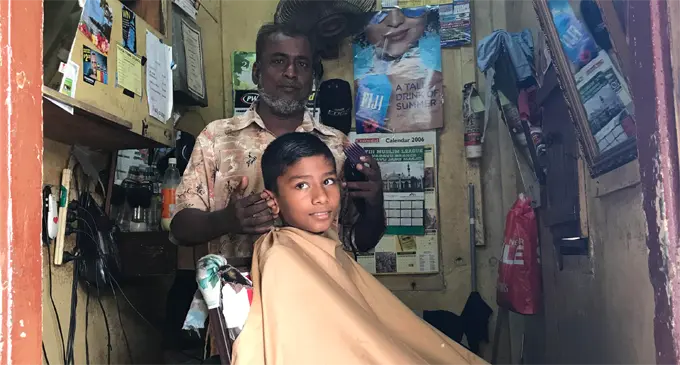 Barber Nazir Khan attending to one of his customers. Photo: Lusiana Banuve