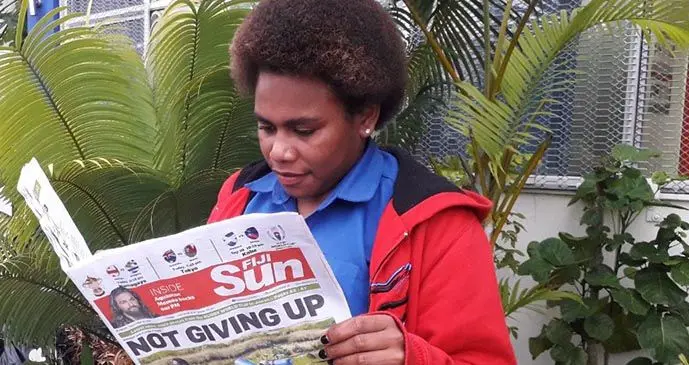 Adi Mere Timaleti reads the Fiji Sun.