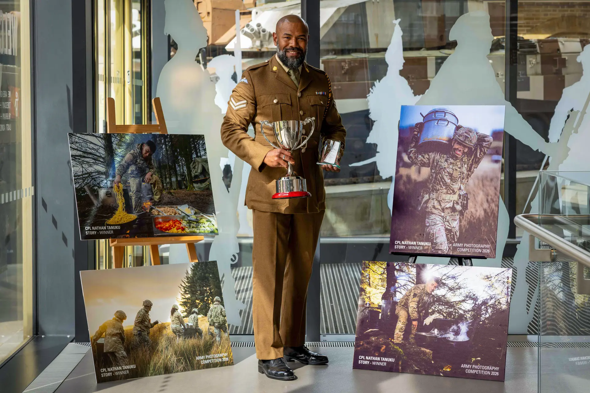 Proud moment: Corporal Nacanieli Gadekilodoni Tanuku poses with his first and second place awards from the British Army Photography Competition, alongside the image series that earned him the prestigious honours.
