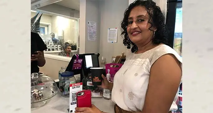 A customer pays for her cup of Weta Coffee, using the M-PAiSA service.