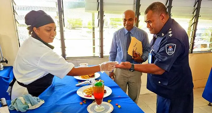 Fiji National University (FNU) Food and Beverages Lecturer, Jaishma Devi, serves a piece of her prepared cake to the chief guest, Northern Division Command, Coordination Centre, Officer in Charge, Inspector George Lagi, while Head of Labasa campus, Pradeep Lal, watches during the College’s open day at Naduna campus in Labasa on October 21, 2022. Photo: Sampras Anand