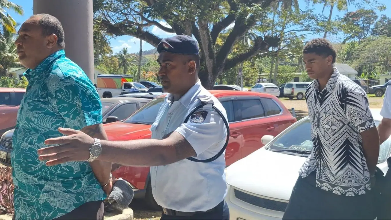 Ratu Vula Ratuva, 51 (left) and Kinijoji Ratuva, 19, is escorted by a police officer at the Sigatoka Magistrate Court on August 13, 2026.