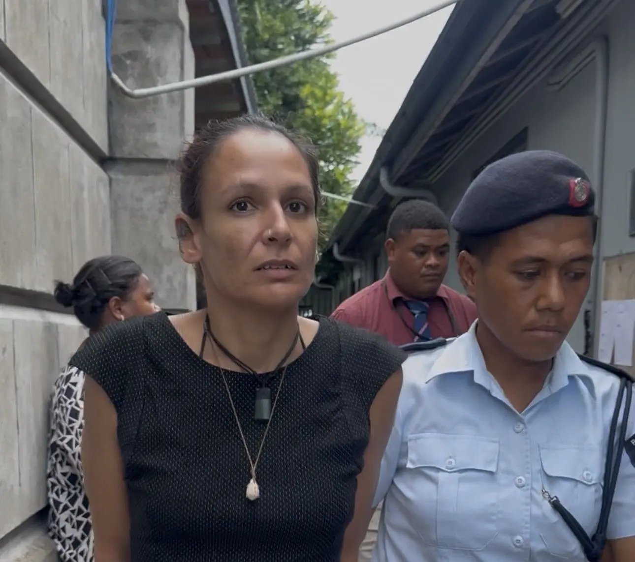 Accused Zoe Maharaj escorted by a police officer outside the Suva Courthouse on February 16, 2026.