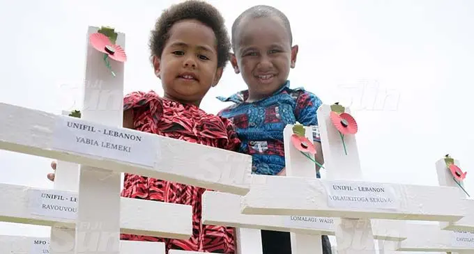 Sala Kotoisuva and Ponijese Kotoisuva next to the cross marked for their late grandfather, Waisale Turaganivalu, during the Remembrance Day ceremony at the National War Memorial ground on November 11, 2020. Their grandfather died while on peace keeping duty in 2011. Photo: Ronald Kumar