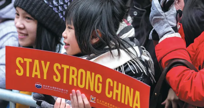 A child holds a sign board while watching a Lunar New Year parade in the Chinatown neighborhood of New York in the United States on Feb 9. [Photo\Agencies]