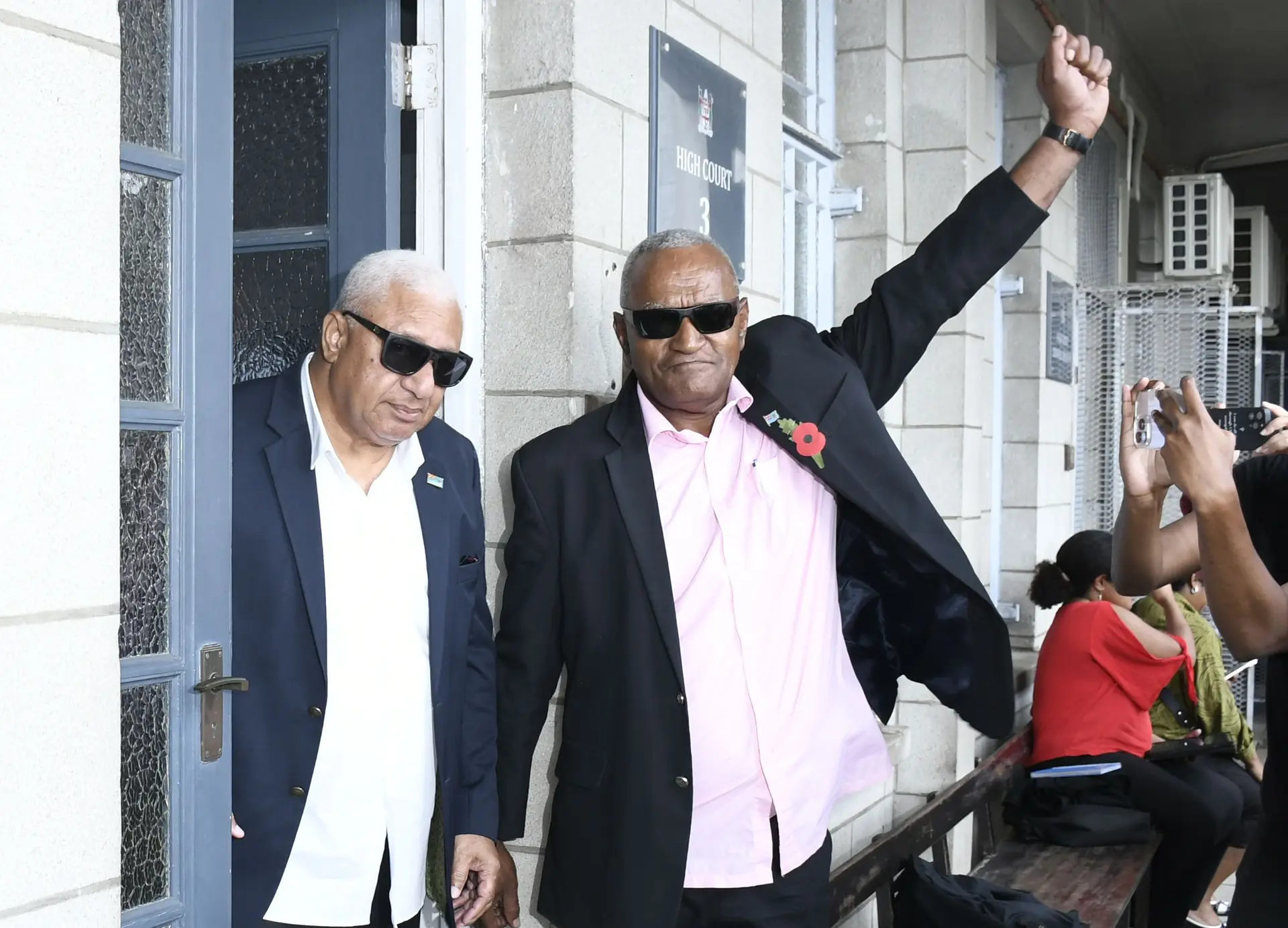 Former Prime Minister Voreqe Bainimarama celebrates with a loyal supporter outside the High Court in Suva following his sentencing on October 22, 2025.