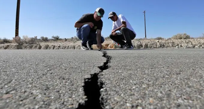 Workers examine a crack in a road in Ridgecrest, California, caused by an earthquake