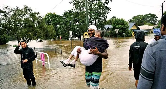 Marika Tabutaci from Tavua carries an elderly woman to safety.  Photo: Sydney Morning Herald