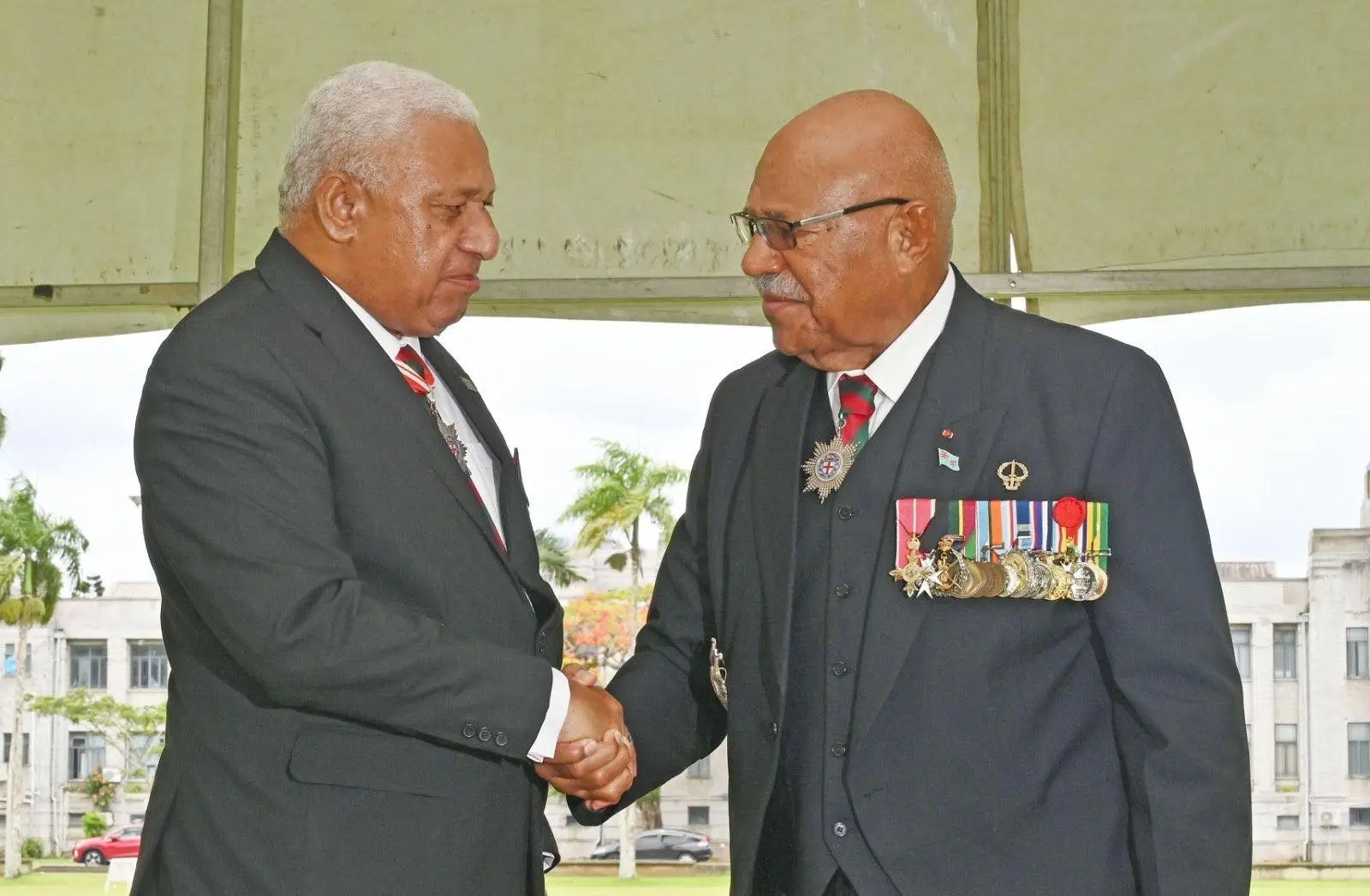 Former military commanders and Prime Ministers Voreqe Bainimarama and Sitiveni Rabuka share a handshake during the welcome ceremony for returning UNAMI peacekeepers in Suva yesterday.