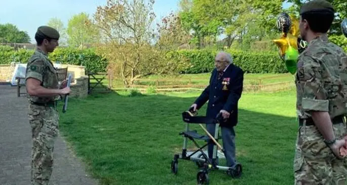 Tom Moore(C), a retired civil servant and Second World War veteran, talks with members of the 1st Battalion, the Yorkshire Regiment, after completing his final lap at his garden in Bedfordshire, Britain, on April 16, 2020. (Photo by Frances Haycock/MOD/Handout via Xinhua)
