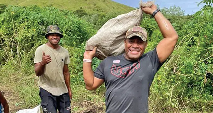 Waisale Serevi carries a bag of cassava as they make their way back to Laselase Village in Nadroga.