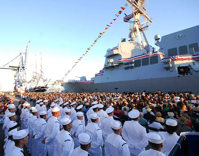 Crew members of the guided-missile destroyer USS Sterett (DDG 104) await the command to “board the ship and bring her to life” during the ship’s commissioning ceremony at the South Locust Point Marine Terminal in Baltimore.