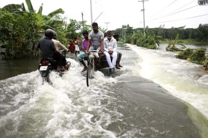 People make their way through a flooded road in Munshiganj on the outskirts of Dhaka, capital of Bangladesh, on July 27, 2020. (Xinhua)