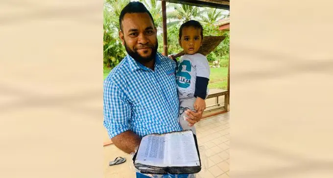 Thomas Wilson with son Junior holding the Bible  with pages intact after their family home in Lami was razed to the ground.