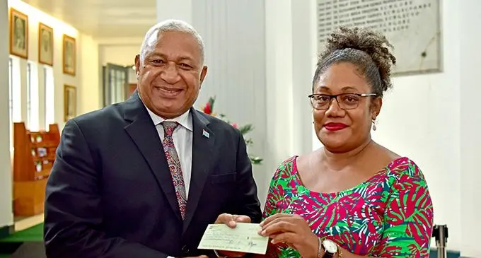 Prime Minister Voreqe Bainimarama presents the cheque to WOWS team leader Viola Lesi. Photo: DEPTFO NEWS