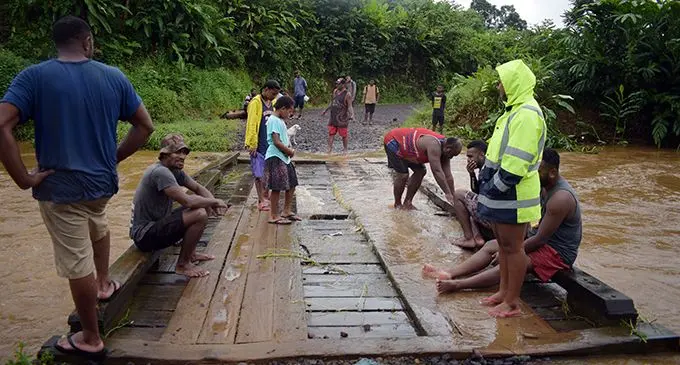  Youths from Waibau Settlement in Tailevu stand by on the bridge to clear the flood debris from damaging the bridge leading to their settlement on April 29, 2020. Photo: Ronald Kumar 