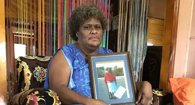 Warrant Officer I Josevata Mokalou's wife Ane holding up a photograph of her late husband.
