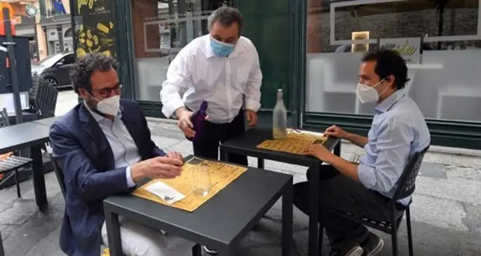 A waiter serves clients at a restaurant in Bologna, Italy, May 18, 2020.  (Photo by Gianni Schicchi/Xinhua)
