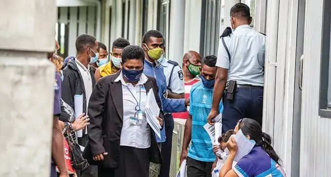 Officials and Police officers with some of those who appeared at the Magistrates Court in Suva for failing to wear masks properly in a public.  Photo: Leon Lord