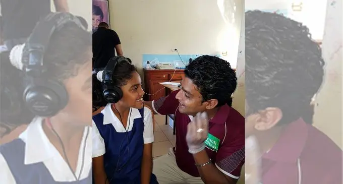 A member of the Frank Hilton audiology team examines a hearing ability of a young student.