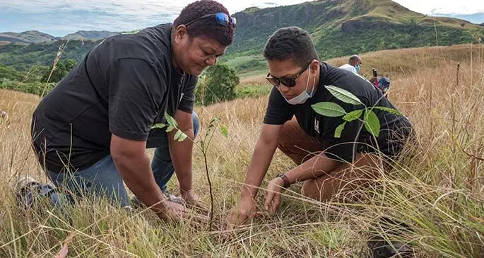 Two members of the FIJI Water team helping plant some of the 1000 tree seedlings.