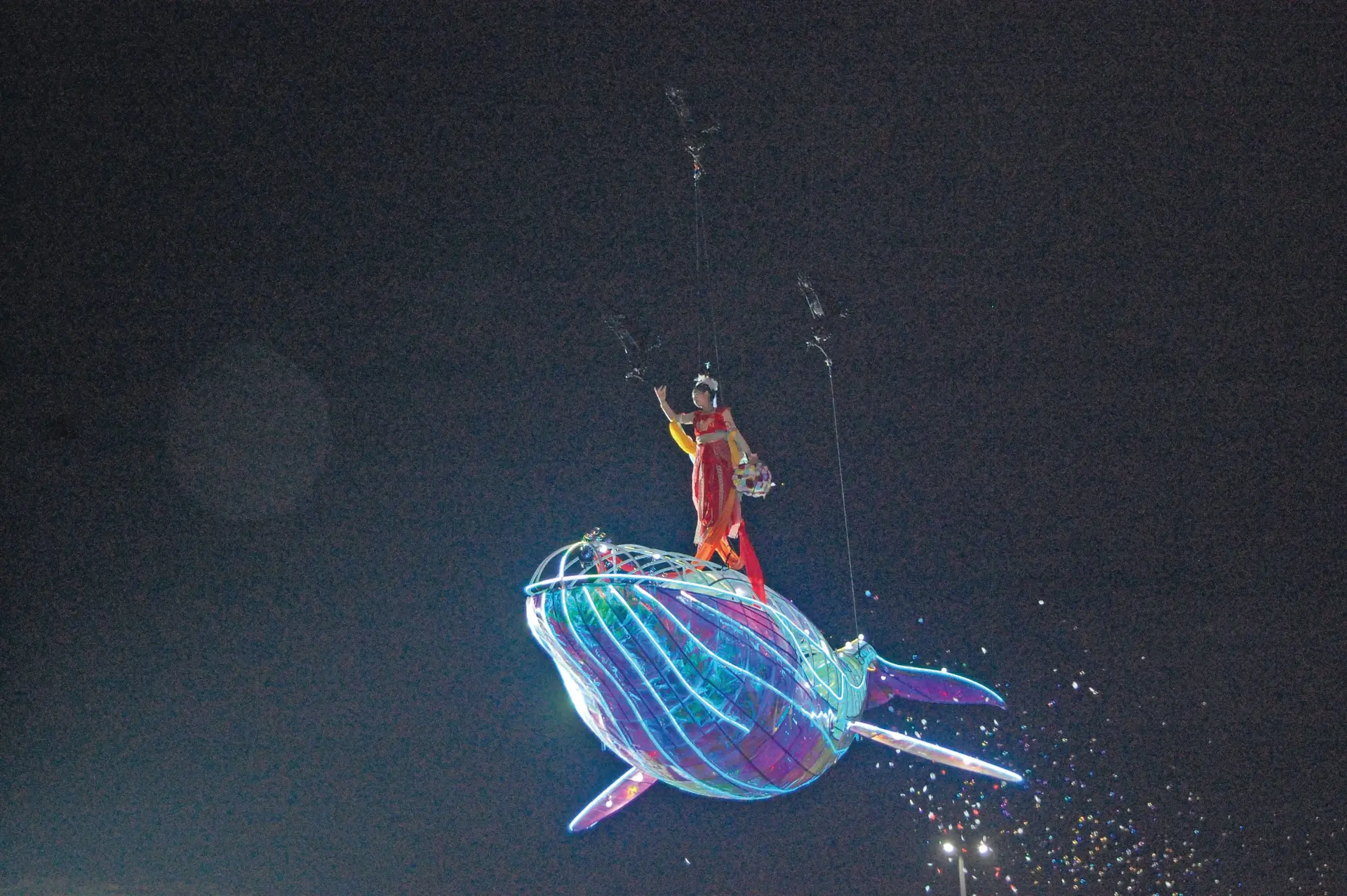 An aerial performance by a woman on the Blue whale (artificial) assisted by wires during the Chaoyang International Light Festival. P