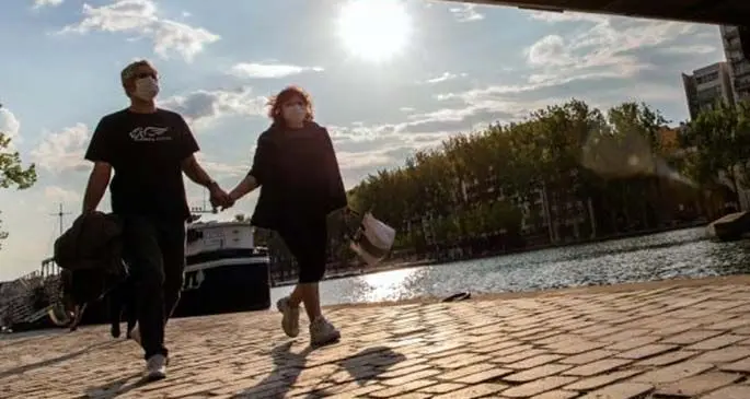 People wearing face masks walk along the Bassin de la Villette in Paris, France, on April 12, 2020. (Photo by Aurelien Morissard/Xinhua)