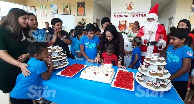 Save Seruvakula (in red), with the Minister for Education, Heritage and Arts, Rosy Akbar, cut the birthday and Christmas cake as Dr Krupali Tappoo (left), and others look on at the Sri Sathya Sai Sanjeevani Medical Centre in Nasese, Suva on December 16, 2019. Photo: Shalveen Chand