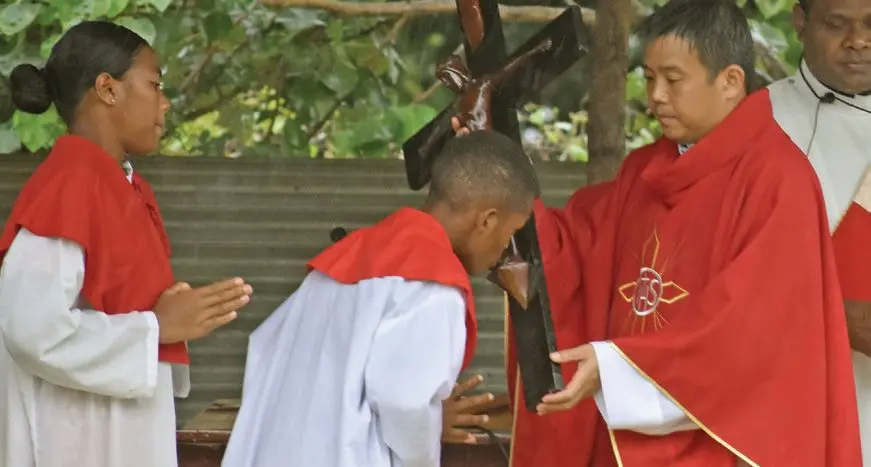 Holy Family Parish Priest Father Euikyun Jung helps an altar boy venerate the Holy Cross at Holy Family Secondary School Ground on March 29, 2024. Photo: Jone Salusalu