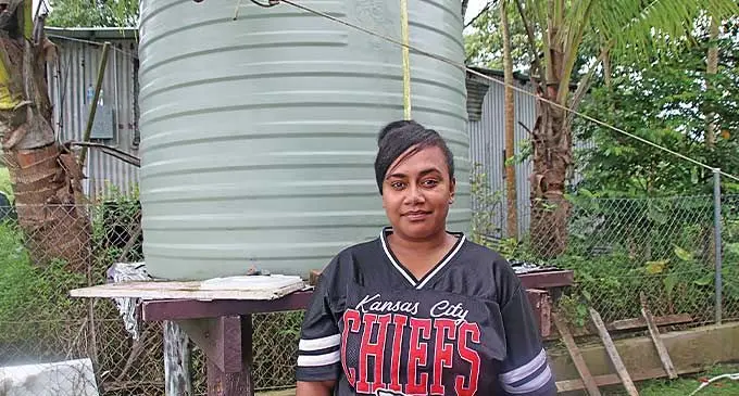 Lia Raloga stands in front of her water tank in Tamavua.