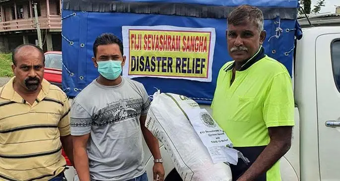From left: Volunteers of Fiji Sevashram Vinod Lal and Anish Chand distributing food ration to cyclone-affected Dharmendra Kumar, in Navosai, Narere.