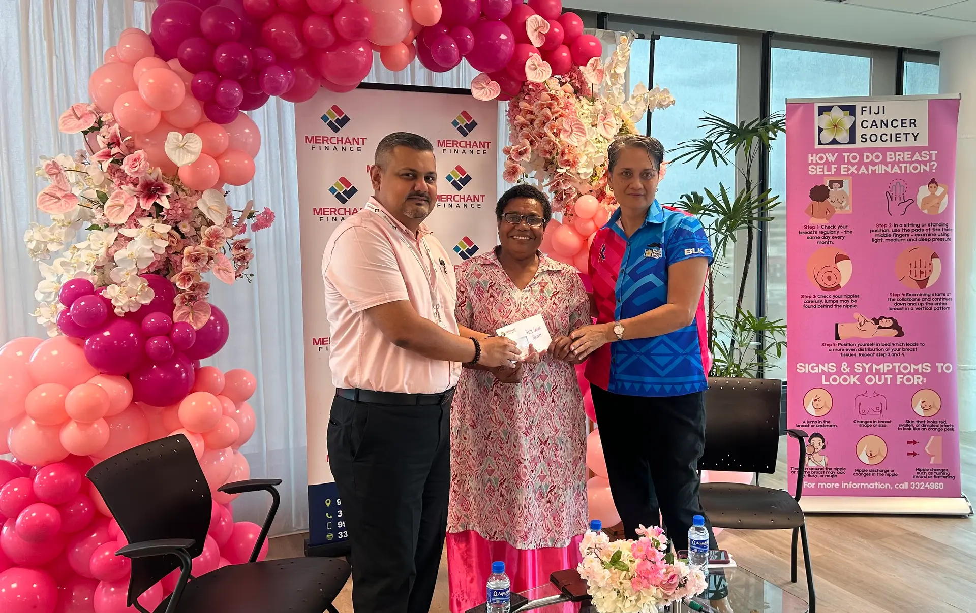Mitesh Kumar presents Merchant Finance's Pinktober donation of $10,000 to Fiji Cancer Society CEO Belinda Chan, joined by breast cancer survivor Mere Bogi.