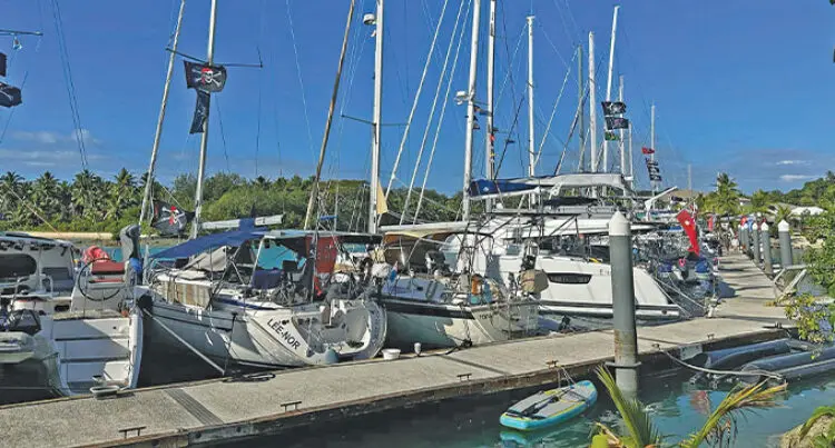A photograph of several yachts anchored side-by-side against a pier.