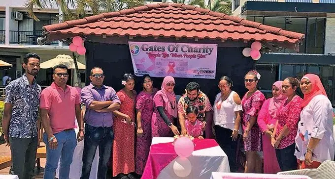 University of Fiji fourth year medical student, Osama Bin Khalid (with garland) cutting the cake with the Gates of Charity club president and founder, Shainaz Ali during the Pinktober awareness celebrations at the Smugglers Cove Resort at Wailoaloa, Nadi.