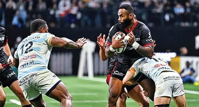 Lyon utility back Semi Radradra (with ball) attempts to escape a tackle as he faces Racing 92 second five eighth Josua Tuisova (left) during their Round 13 match in the Top 14 competition at Paris La Défense Arena on December 30, 2024 . Photo: Icon Sport